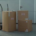 Three cardboard boxes on a dolly, ready for shipping outside a warehouse.